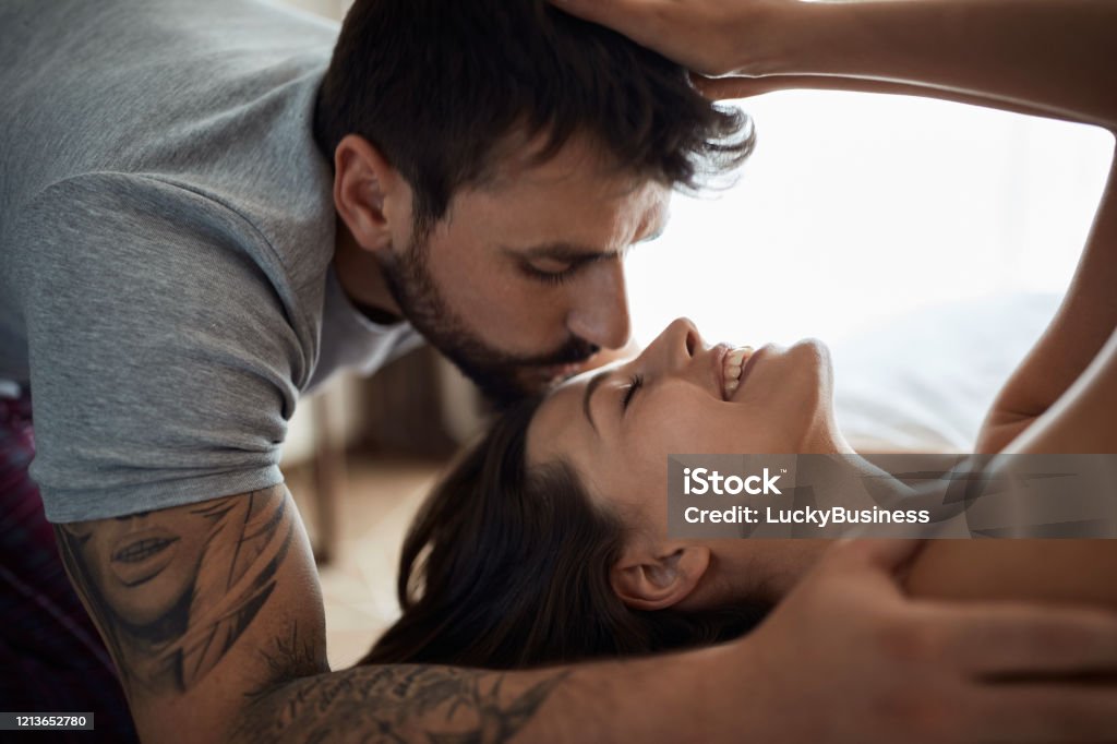 couple in bed being intimate with each other and kissing. beautiful couple in bed being intimate with each other and kissing. Adult Stock Photo