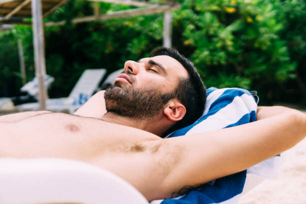 istock Young man sunbathing on a deckchair in nature 1213652909
