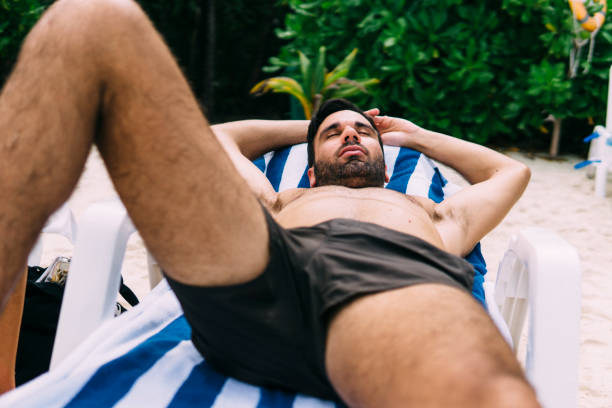 istock Young man sunbathing on a deckchair in nature 1213653077