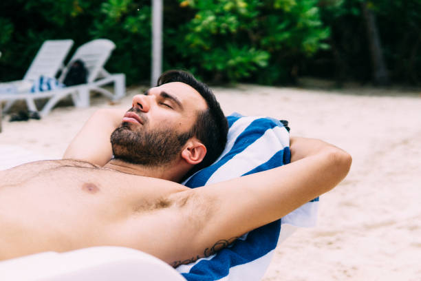 istock Young man sunbathing on a deckchair in nature 1213653086