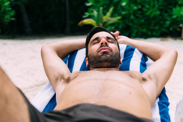 istock Young man sunbathing on a deckchair in nature 1213653657