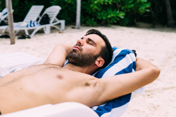 istock Young man sunbathing on a deckchair in nature 1213653681