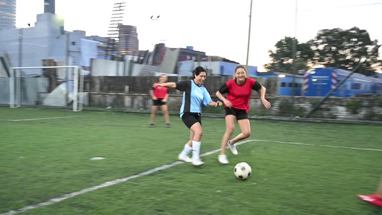 Mid adult female footballer dribbling around opponent