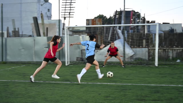 Hispanic female footballer dribbling by opponent and scoring
