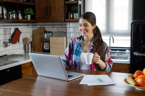 istock Pregnant woman sitting in kitchen and working on laptop computer 1213657241
