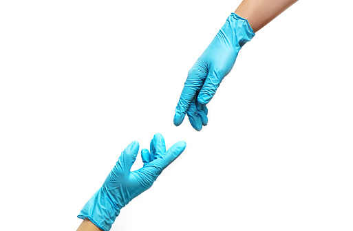 Hands of people in medical gloves reaching out for each other on white background. COVID-19 pandemic concept.