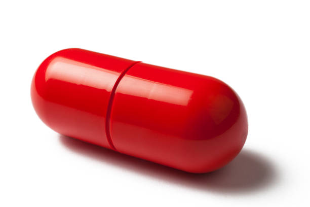 kapsułka red pill wyizolowana na białym tle - red pills zdjęcia i obrazy z banku zdjęć