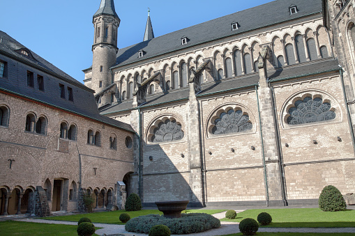 Inner yard and arcade Kreuzgang of Bonner Muenster church in Bonn. Medieval church with inner yard as place of silence for relaxing. Inside of yard are graves of medieval times. In center of cross shaped pathways is a fountain.
