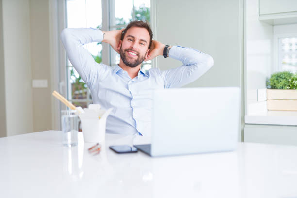 istock Business man eating take away asian noodles food while working using computer laptop and smiling 1213664501