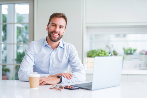istock Handsome man working using computer laptop and drinking a cup of coffee with a happy face standing and smiling with a confident smile showing teeth 1213664542