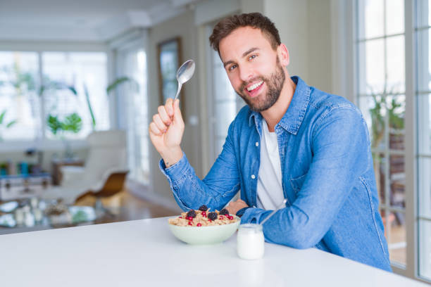 istock Handsome man having breakfast eating cereals at home and smiling 1213664923