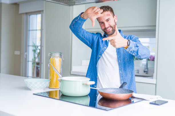 istock Handsome man cooking italian spaghetti pasta at the kitchen smiling making frame with hands and fingers with happy face. Creativity and photography concept. 1213665107