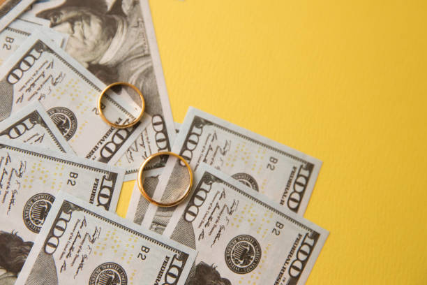 istock Golden wedding rings on banknotes background. Marriage of 1213665128