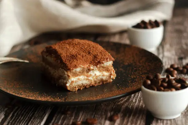 Tiramisu cake on a plate. Romantic composition with coffee and other elements