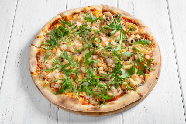 istock Fresh italian pizza with shpimps and squid on wooden table 1213673509
