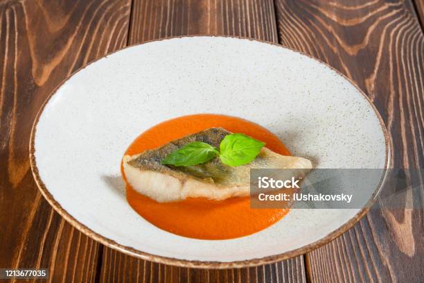 Plate Of Fish Fillet With Pumpkin Sauce On A Wooden Table Stock Photo - Download Image Now