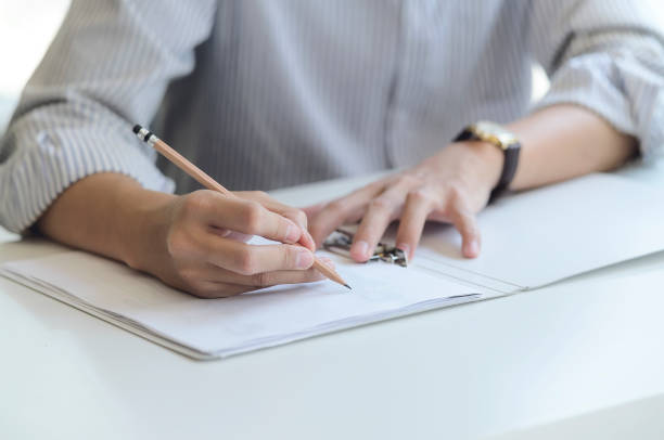 istock Man writing or drawing with pencil on paper. Closeup view. 1213678259