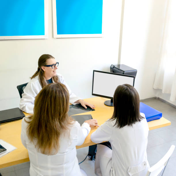 istock Three doctors sitting around a conference table locking at screem. 1213679414
