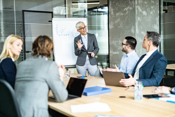Happy mature CEO talking to her team during a presentation in the office.