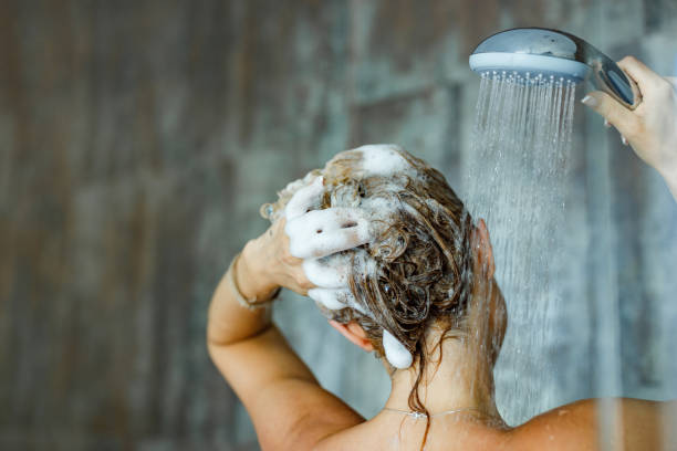 Washing hair with shampoo! Back view of a woman washing her hair with a shampoo in bathroom. Copy space. body care shower stock pictures, royalty-free photos & images