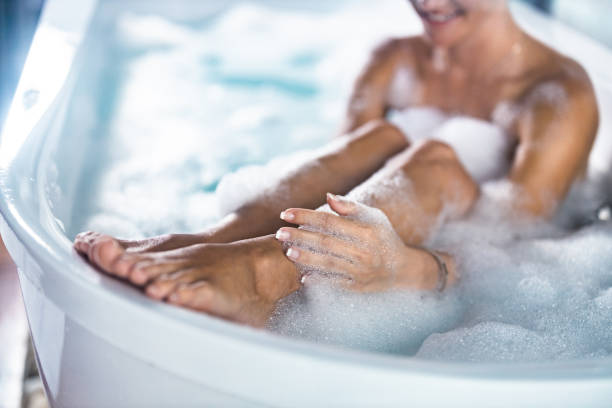 крупным планом женщина моет ноги в пузырчатой ванне. - human leg women shower water стоковые фото и изображения