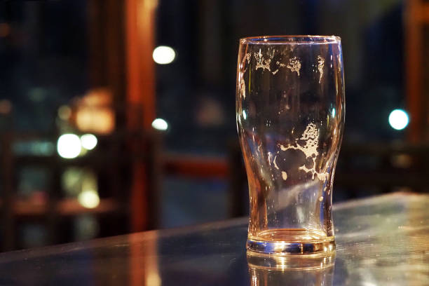 bicchiere di birra vuoto su un tavolo in un bar buio, pub - cup of beer foto e immagini stock