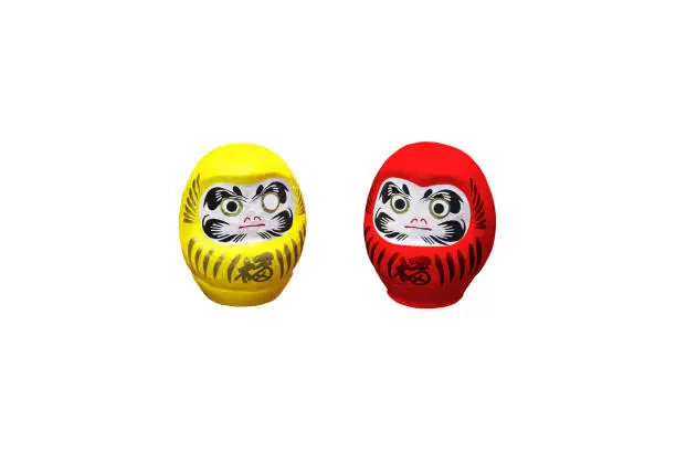 Photo of Red and yellow daruma dolls isolated on white background. Japanese traditional doll representing Bodhidharma, deity that brings happiness. Fulfilled wishes