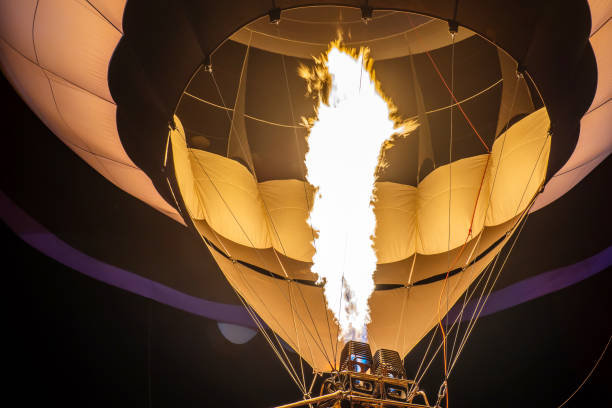 preparation of a hot air balloon for flight by heating the air with a gas burner on evening in a summer day on a festival of ballooning - inflating balloon blowing air imagens e fotografias de stock