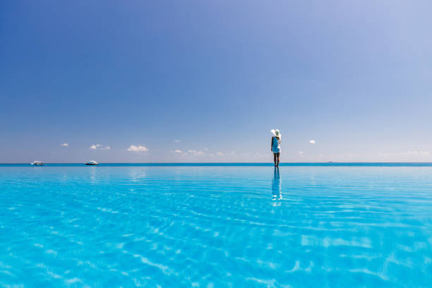 istock Back view of a woman looking at sea view from an infinity pool. 1213683472