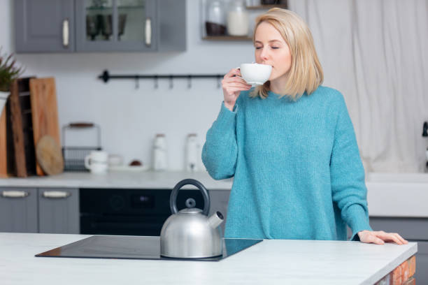 istock blonde lady with cup of coffee at kitchen 1213685092