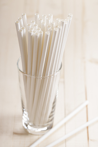 white paper straws in glass on wooden background, Sustainable lifestyle concept
