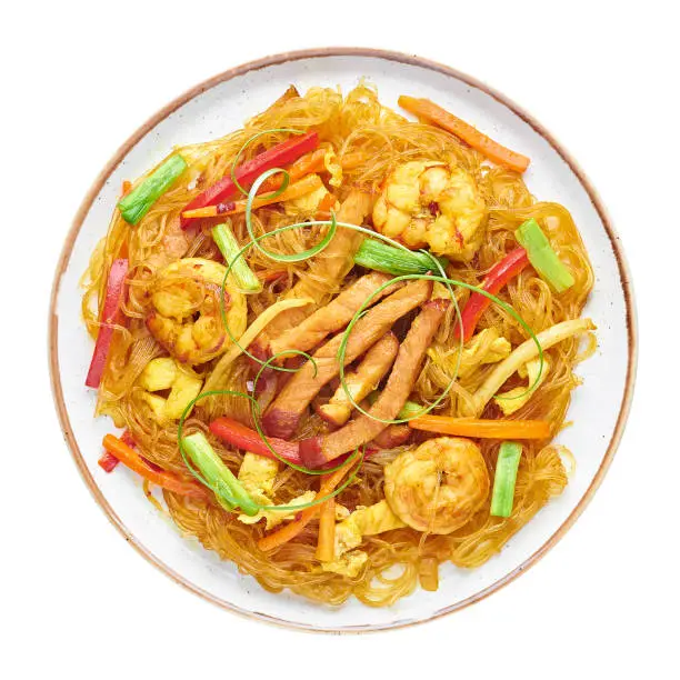 Singapore Mei Fun in plate isolated on white background. Singapore Noodles is chinese cuisine dish with rice noodles, prawns, char siu pork, carrot, red onion, napa cabbage. Chinese food. Top view