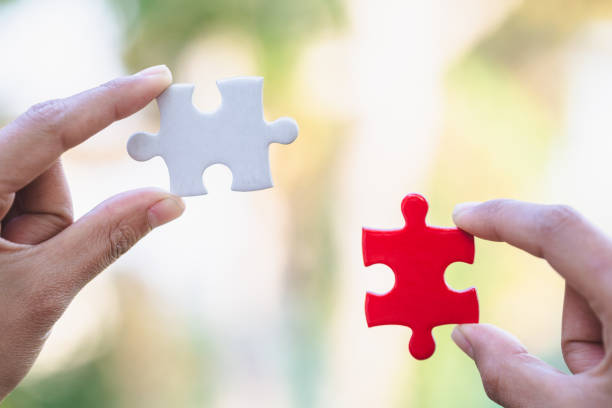 istock Jigsaw connection between white and red jigsaw puzzles, Jigsaw puzzle in the hand of a businessman,  Business team assembling Jigsaw puzzle. 1213687378