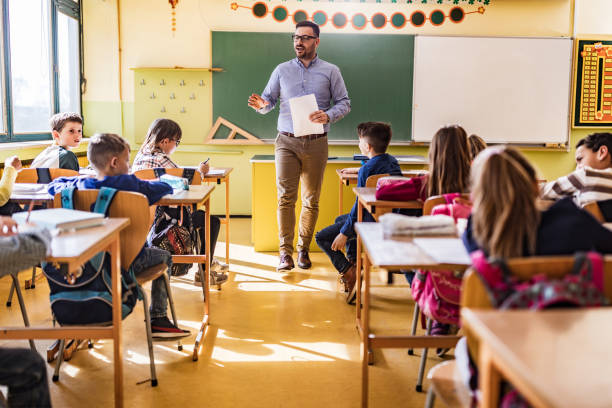 istock Happy male teacher giving a lecture at elementary school. 1213690152