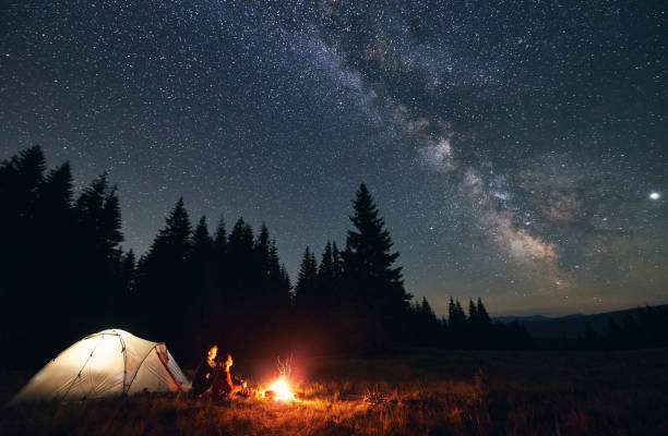 istock Couple enjoying starry night sky near campfire. 1213691589