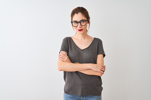 Redhead woman wearing casual t-shirt and glasses standing over isolated white background happy face smiling with crossed arms looking at the camera. Positive person.