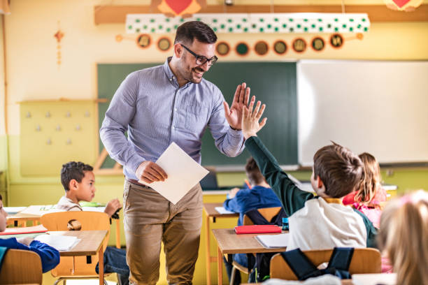 istock Happy teacher and schoolboy giving each other high-five on a class. 1213693379