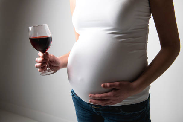 istock Pregnant women with wine glass on studio white 1213694953