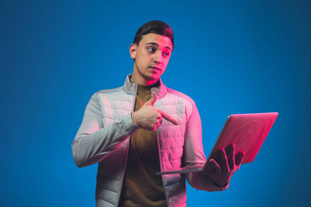 istock Caucasian man's portrait isolated on blue studio background in neon light 1213696581