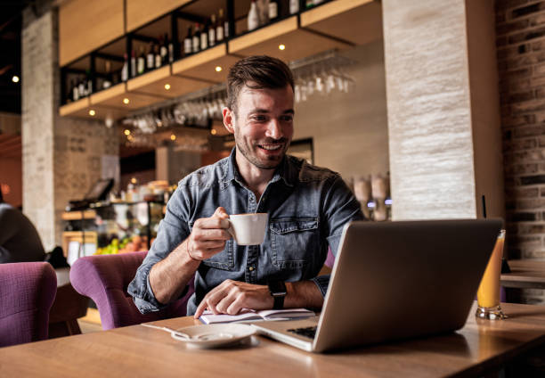 istock Young man sitting at cafe shop and working on laptop. 1213697126