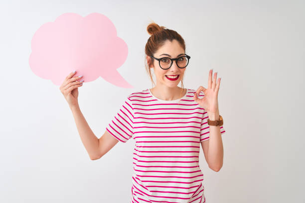 istock Redhead woman wearing glasses holding cloud speech bubble over isolated white background doing ok sign with fingers, excellent symbol 1213698027