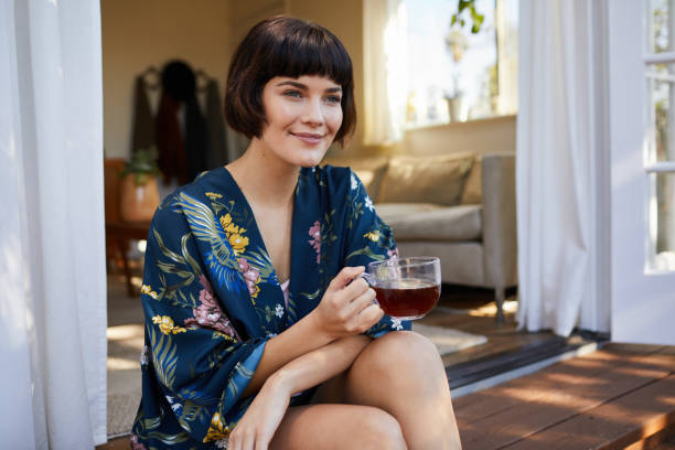 istock Young woman smiling while drinking tea on her patio 1213698394