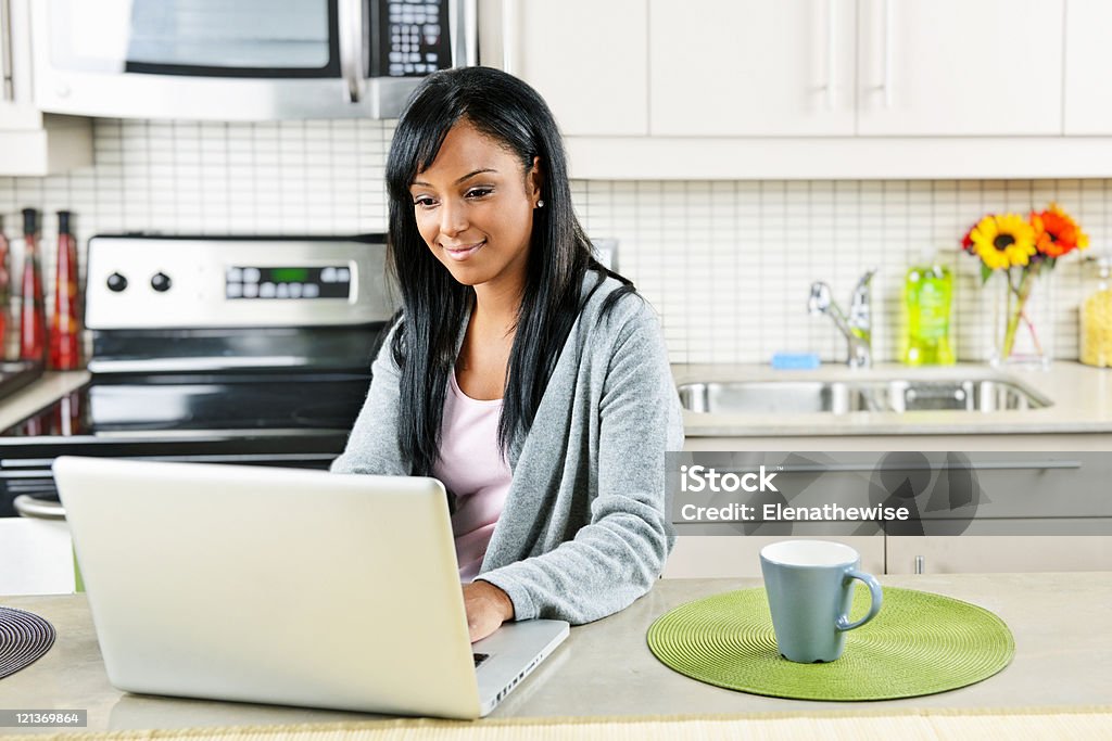 Kobieta za pomocą komputera w kuchni - Zbiór zdjęć royalty-free (Afroamerykanin)