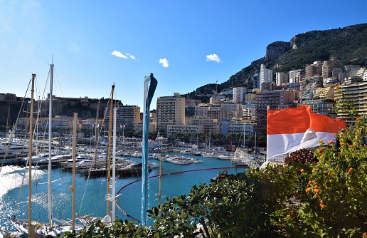 Monte Carlo, Monaco - December 22 2019: Port Hercules with Monaco flag and clear blue sky