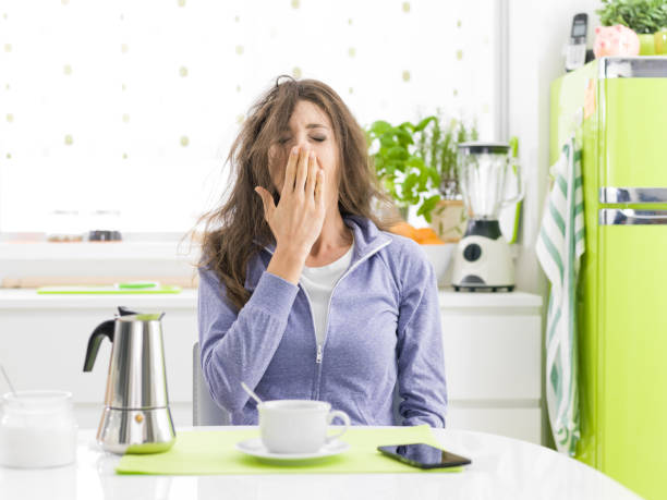 donna stanca che fare colazione a casa - yawning women drink coffee cup foto e immagini stock