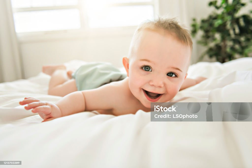 cute baby boy lying on a white bed A cute baby boy lying on a white bed Baby - Human Age Stock Photo