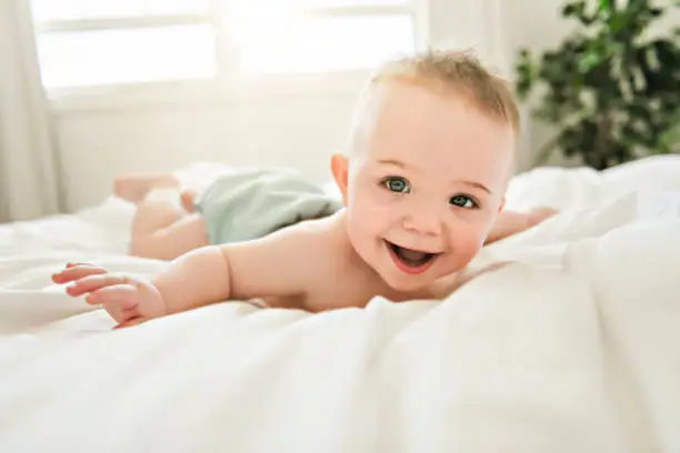 Photo of cute baby boy lying on a white bed