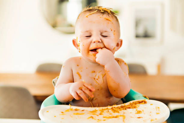 istock Little baby boy eating her dinner and making a mess 1213703424