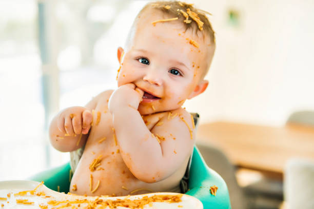 istock Little baby boy eating her dinner and making a mess 1213703436