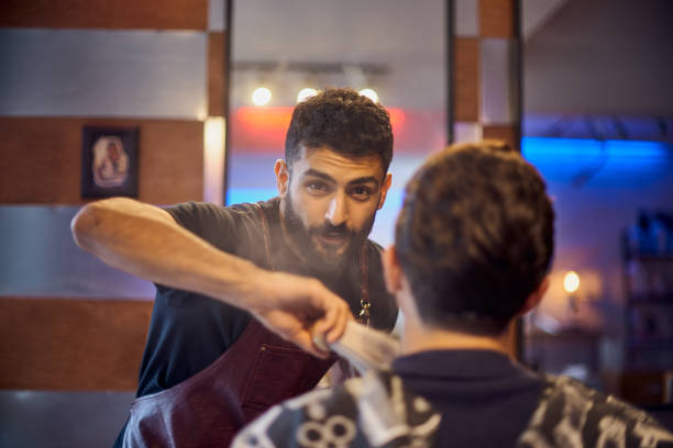 istock Shaving process of beards in Barbershop. Master makes the client shave his beard with vintage straight razor. 1213704726